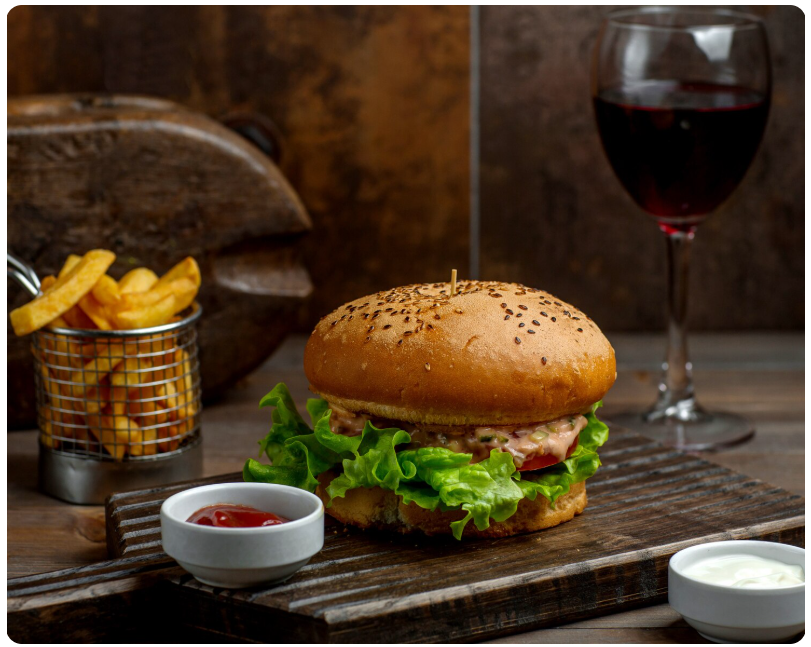 Copa de vino tinto acompañando una hamburguesa con patatas fritas, ejemplo de maridaje inesperado y moderno.